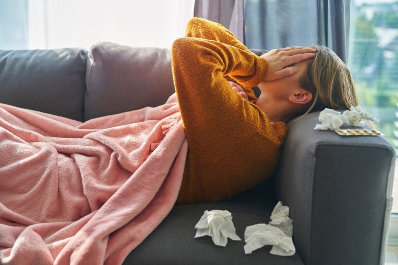 A woman sick and holding tissues during cold and flu season.