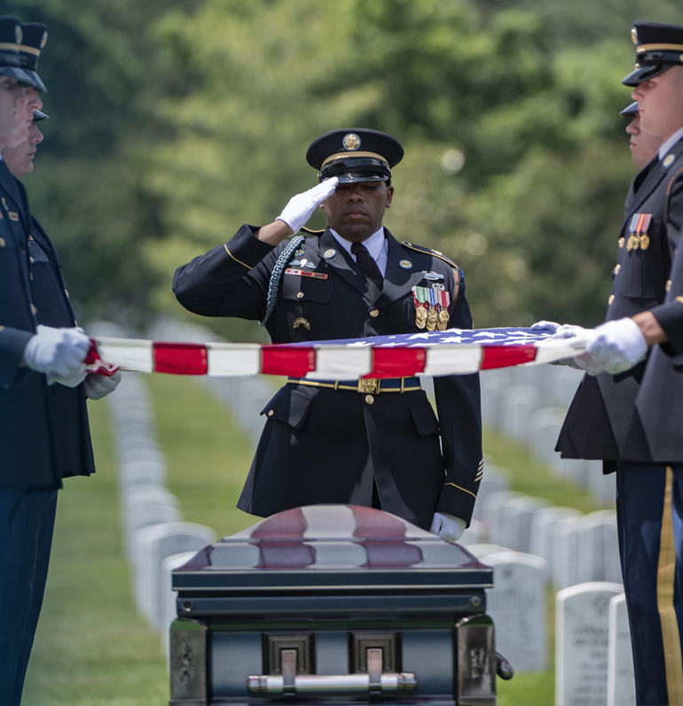 Soldiers holding American flag over casket of fallen soldier