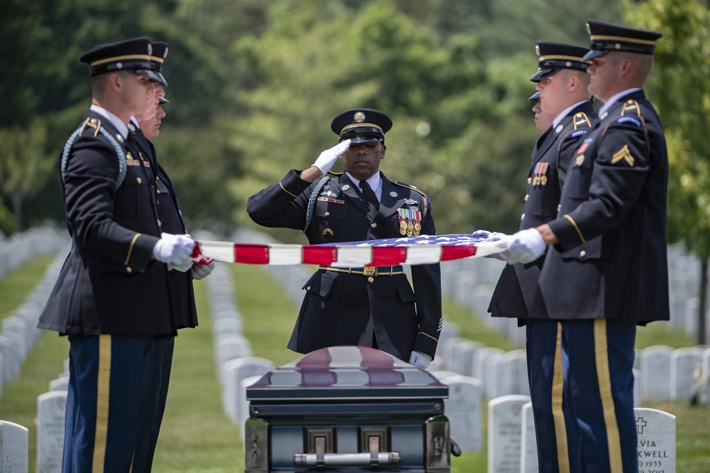 soldiers holding a flag over a casket of a fallen soldier