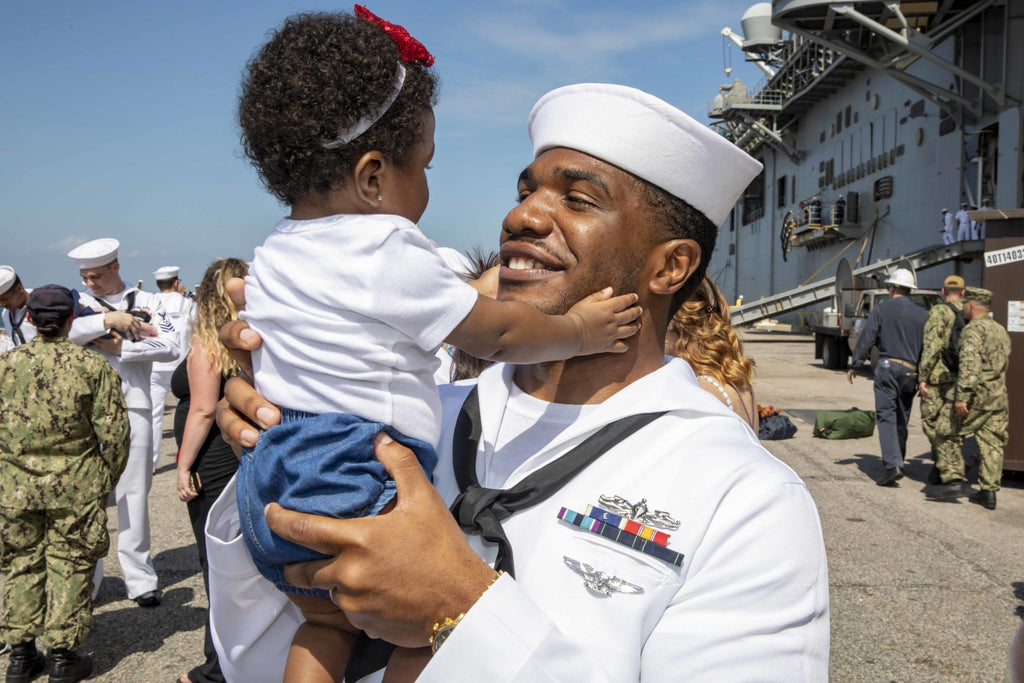Navy Sailor holding his daughter smiling