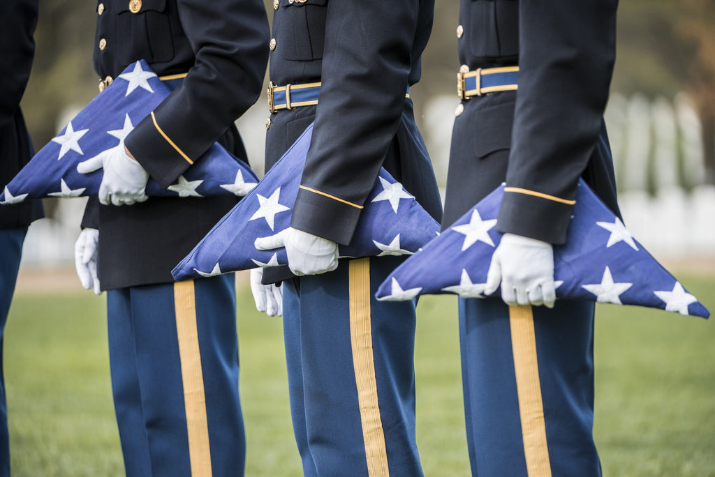 Soldiers holding folding flags at a funeral